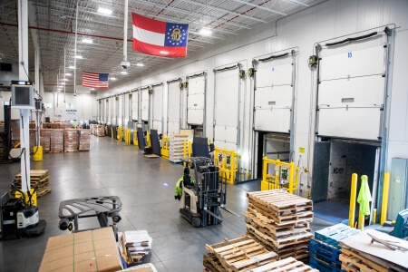 Interior view of a Lineage Logistics facility in Atlanta, Georgia, featuring a modern cold storage warehouse with multiple loading docks and efficient forklift operations.