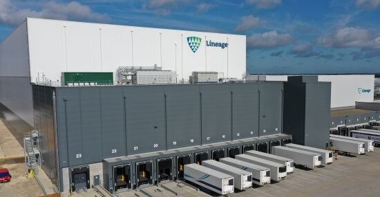 Exterior view of a Lineage Logistics automated cold storage facility with multiple loading docks and trucks, designed for efficient supply chain operations.