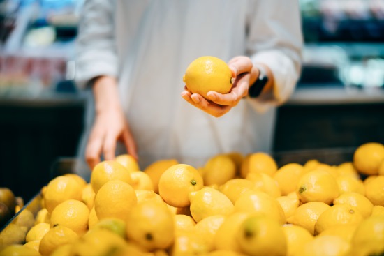 A lemon is handled by a consumer at a market