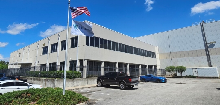 Exterior view of Lineage’s Dignan cold storage facility in Jacksonville, Florida, showcasing the modern building design and prominently displayed flags under a clear blue sky.