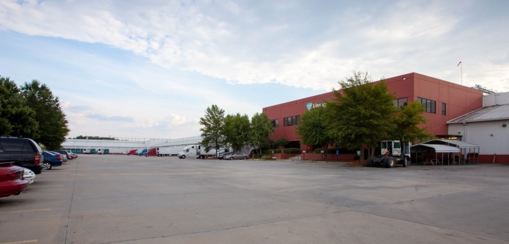 Exterior view of Lineage’s McDonough - 200 King Mill cold storage facility, featuring a red-brick office building, spacious parking lot, and multiple docked trucks.