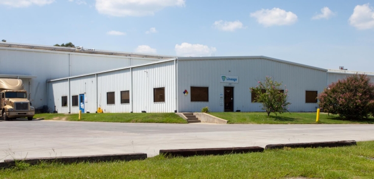 Exterior view of Lineage’s Unadilla cold storage facility near Atlanta, Georgia, featuring a white warehouse with a small office entrance, parked truck, and surrounding greenery.