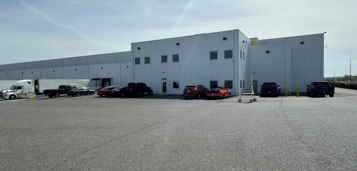 Exterior view of Lineage's Pasco cold storage warehouse in Washington, featuring a modern white facility with parked trucks, cars, and spacious lot for logistics operations.