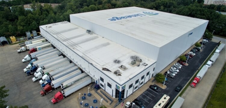 Exterior view of Lineage's College Park cold storage warehouse in Atlanta, GA, with multiple loading docks, parked trucks, and surrounding green landscape, supporting efficient cold chain logistics.