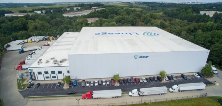 Aerial view of Lineage's College Park cold storage facility in Atlanta, GA, featuring a large warehouse, multiple truck bays, parked trailers, and surrounding green landscape, highlighting advanced logistics infrastructure.