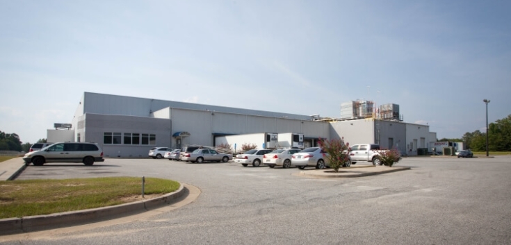 Exterior view of Lineage’s Macon cold storage facility in Atlanta, Georgia, featuring a white warehouse with loading docks, fenced perimeter and a small office area.