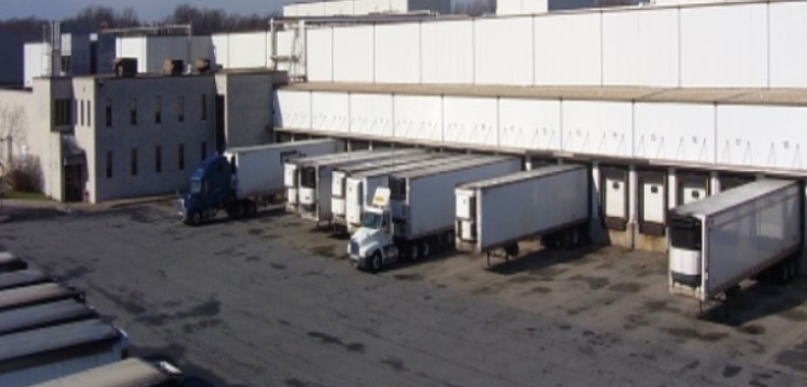 Lineage's New Castle cold storage warehouse in Delaware, showing multiple loading docks with semi-trucks and trailers parked for cold chain logistics operations.