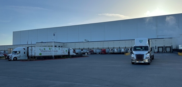 Lineage's Pasco cold storage warehouse in Washington, featuring multiple loading docks, parked trucks, and a large paved yard at sunrise, supporting efficient cold chain operations.