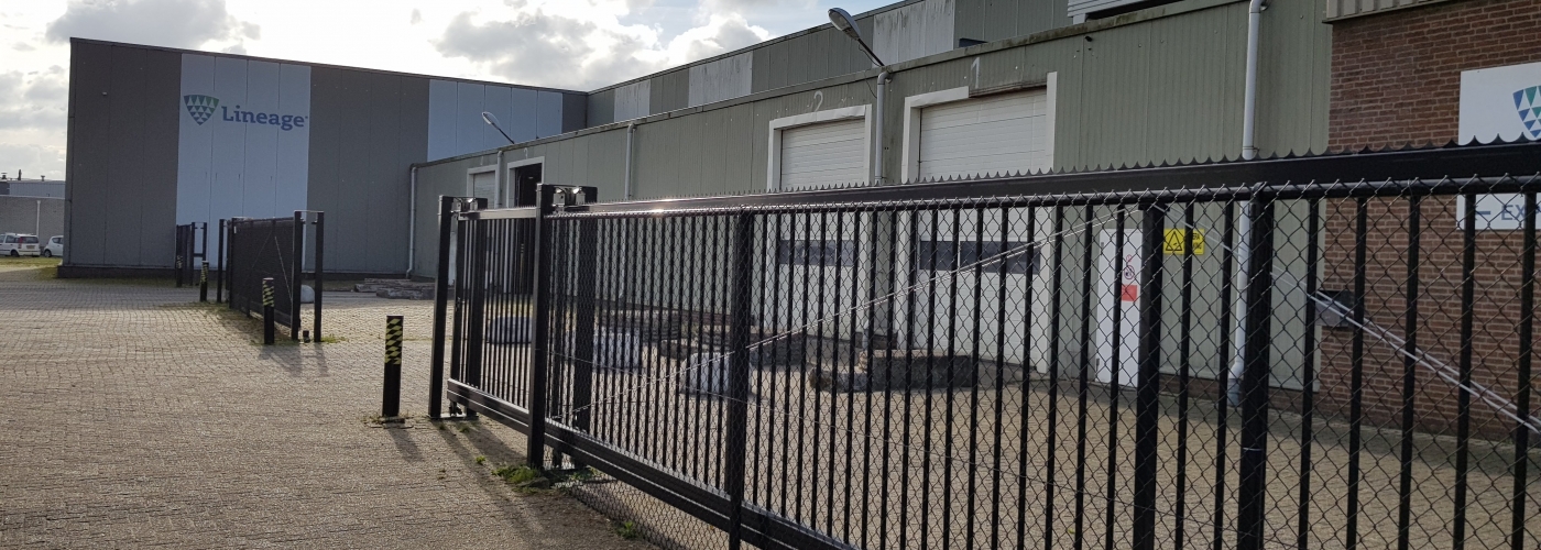 Exterior photo of Lineage's Hoogerheide facility with gate in foreground.