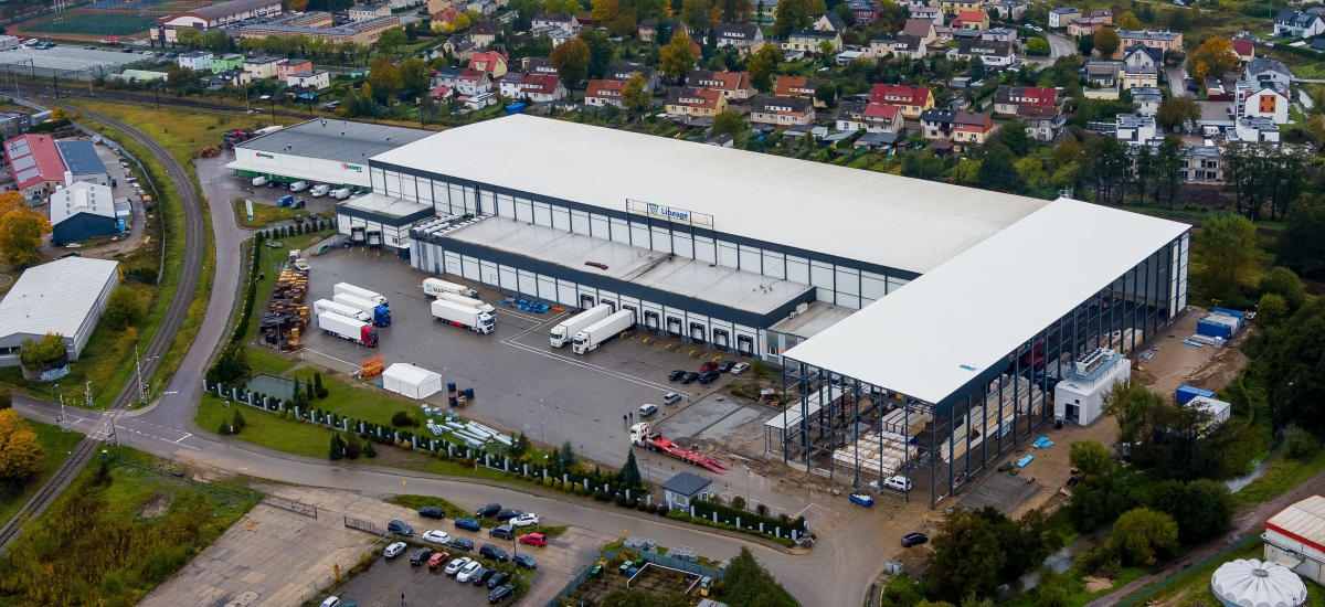 An aerial view of Lineage's newly expanded temperature-controlled warehouse facility in Lebork, Poland shows the large warehouse with several trucks parked nearby.