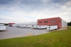 Side view of Lineage’s McDonough - 200 King Mill cold storage facility, showcasing docked refrigerated trailers, a red-brick structure, and open loading areas.