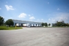 Side view of Lineage’s Unadilla cold storage facility near Atlanta, Georgia, showcasing docked refrigerated trailers, surrounding greenery, and open parking areas under a clear blue sky.